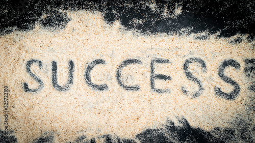Top view of success text written on white sand