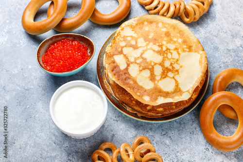 Shrovetide Maslenitsa festival meal. Russian pancake blini with raspberry jam, honey, fresh cream and red caviar,sugar cubes,cottage cheese,bubliks on light background photo