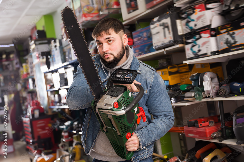 Positive male is buying new chainsaw