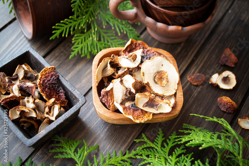 dried mushrooms cep and boletus in wooden bowl on dark wooden background