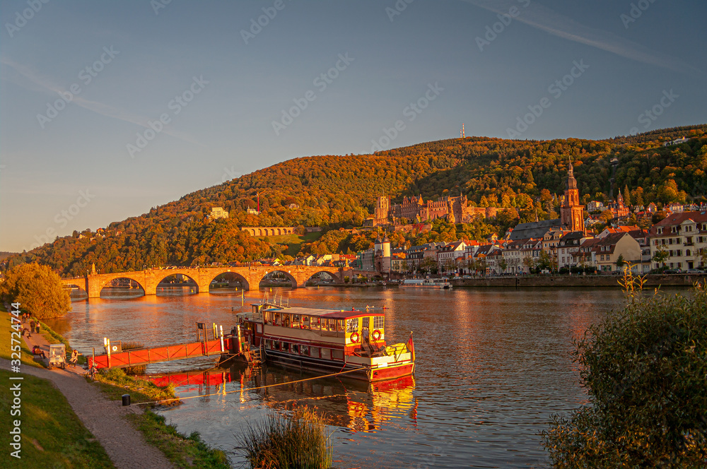 Fototapeta premium Stunning reddish sunset over the old town, castle and main city bridge in Heidelberg, Germany, panoramic view