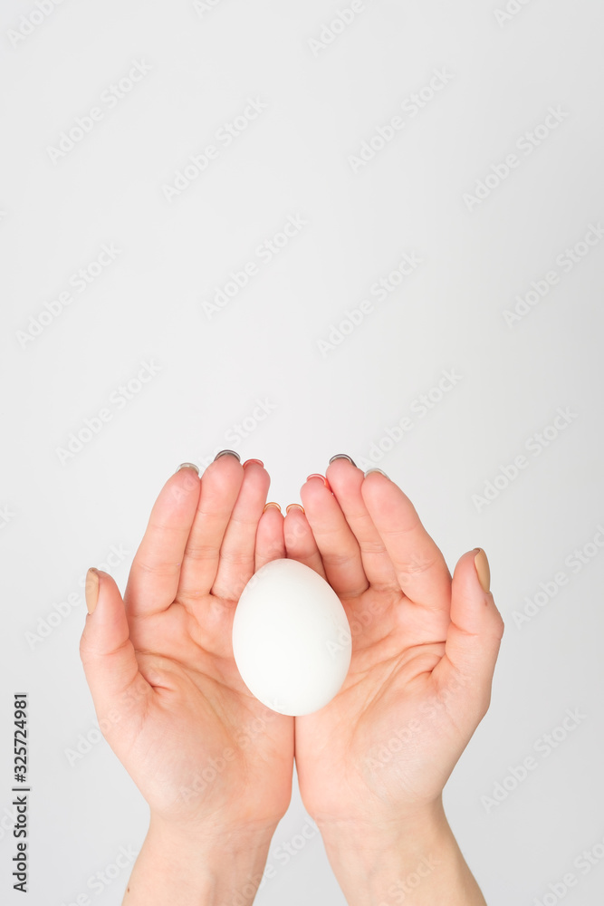 Hand holds a white egg on a white background Hand holds a white egg on a white background