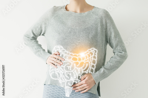 Woman in casual grey clothes suffering from indigestion pain, highlighted vector visualisation of intestine photo