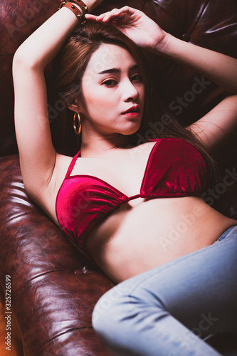 Cute asian woman laying on sofa. Sexy look, top view. For seductive sensuality and provocative desire concept. Vintage filter look. © Baan Taksin Studio