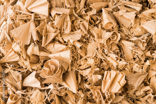 Beautiful spiral curled wooden sawdust in texture detail. Abstract close-up of wood shavings scattered on pile as decorative background. By-product of milling, routing or drilling. Woodworking waste.