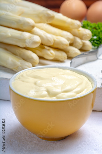 White hollandaise sauce in bowl, traditional sauce for dishes with cooked white asparagus