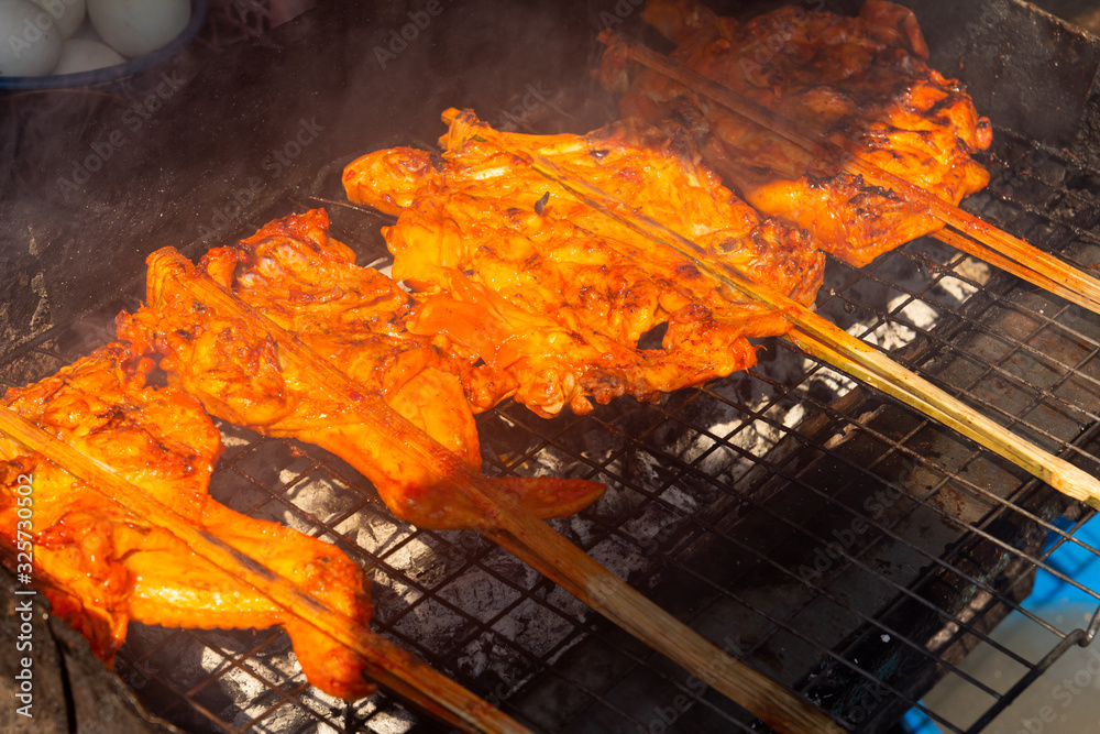 Grilled chicken with skewer cooked on charcoal barbecue stove background