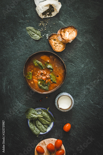 green lentil soup with tomatoes and vegetables on a dark background on the table. copy space flat lay