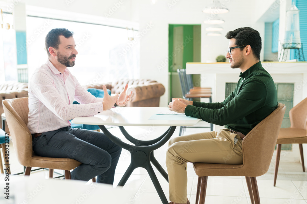 Recruiter Taking Interview Of Mid Adult Man In Office Recruiter Taking Interview Of Mid Adult Man In Office