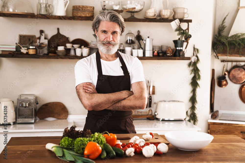 Image of serious mature man in apron standing with hands crossed Image of serious mature man in apron standing with hands crossed