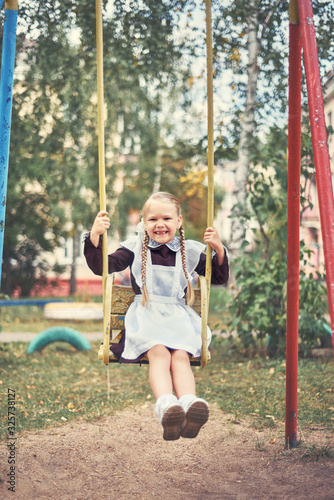 happy little girl is swinging on the playground.