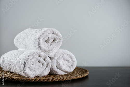 Clean rolled bath towels and wicker mat on dark grey table. Space for text