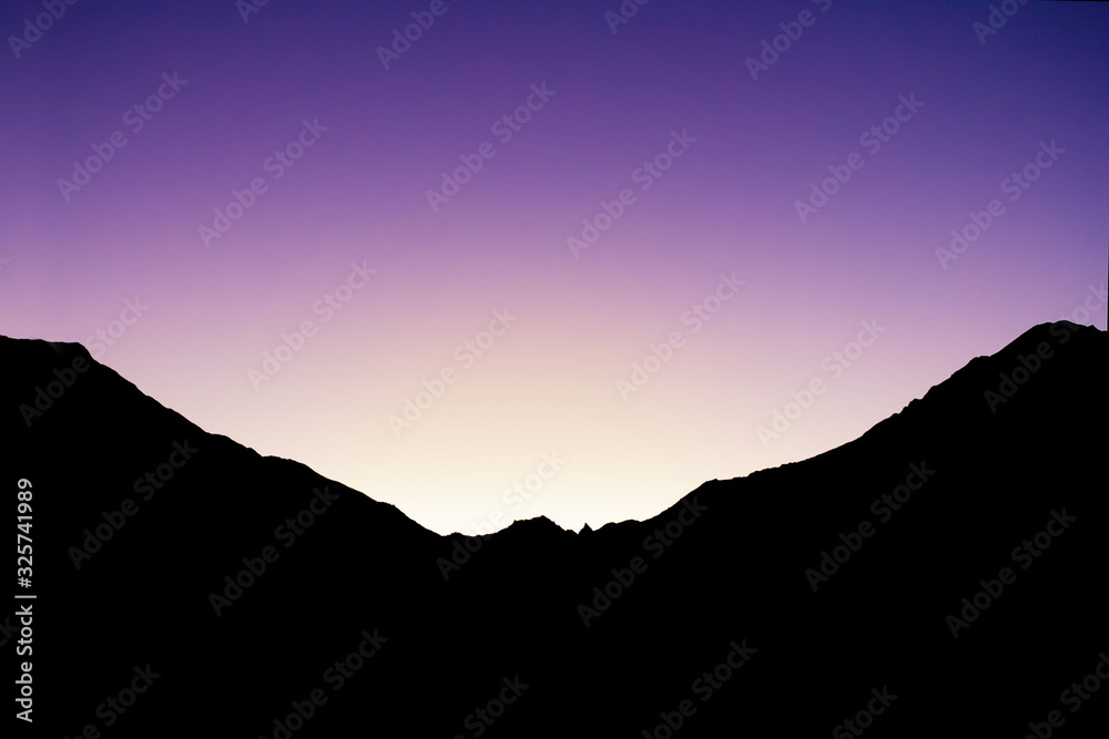 Obraz premium black contour of mountains backlit by the setting sun