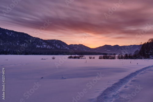 Winter mountain landscape. Orange-purple winter sunset in the mountains. Republic of Altai. Russia