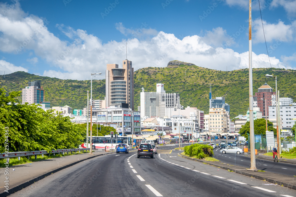 Naklejka premium PORT LOUIS, MAURITIUS - APRIL 28, 2019: City traffic with buildings and beautiful landscape