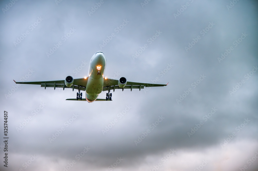 Fototapeta premium Airplane landing against a cloudy day