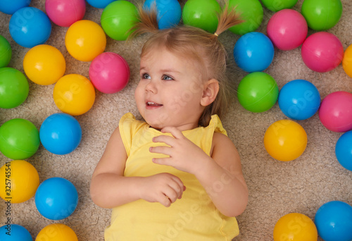 Cute little child playing with balls on floor, top view