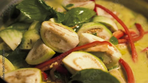 Someone putting ingredients on a pot full of green curry. Making of Green curry with chicken. Thai food. slow motion.