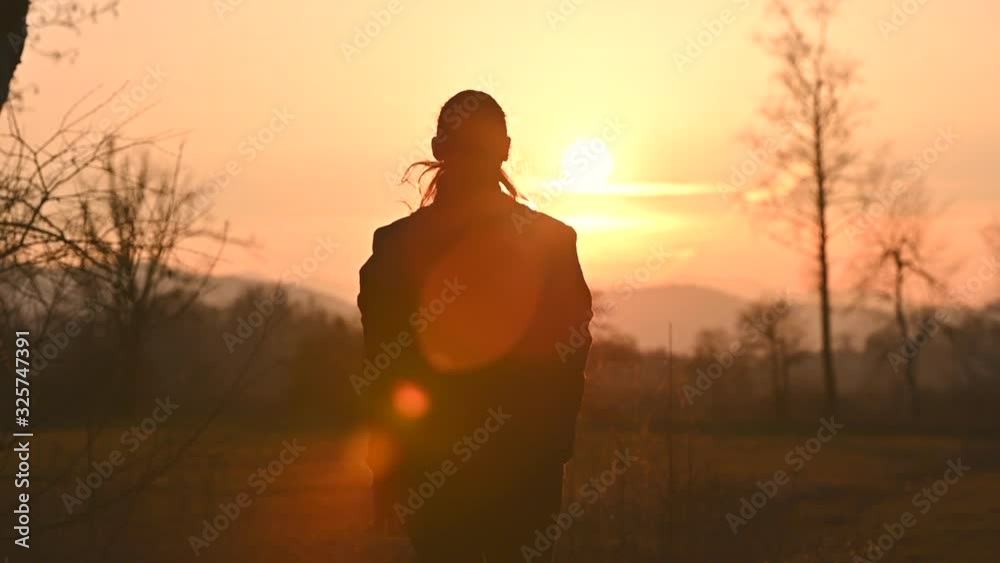 SLO MO Woman doing jumping jacks while looking into the setting sun SLO MO Woman doing jumping jacks while looking into the setting sun