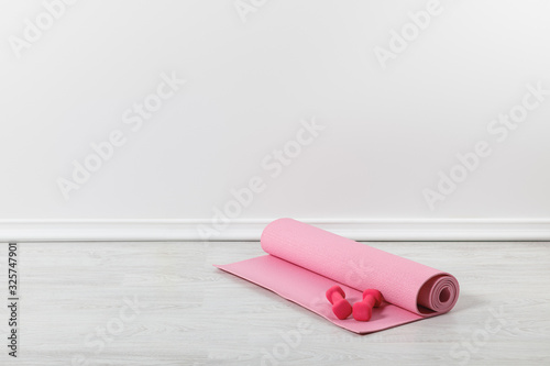 pink fitness mat and dumbbells on floor photo
