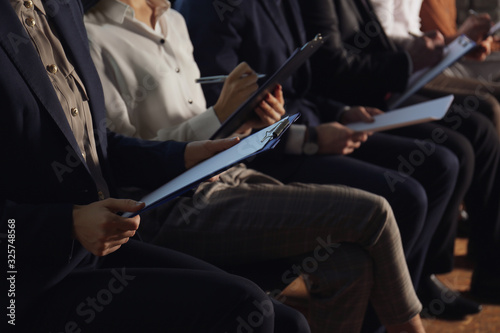 Young woman with clipboard waiting for job interview in office hall  closeup