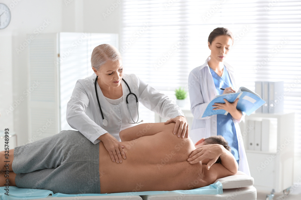 Obraz premium Female orthopedist examining patient's back in clinic