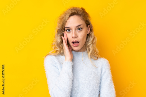 Young blonde woman isolated on yellow background surprised and shocked while looking right © luismolinero