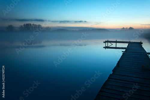 Foggy blue evening at the lake with a long bridge