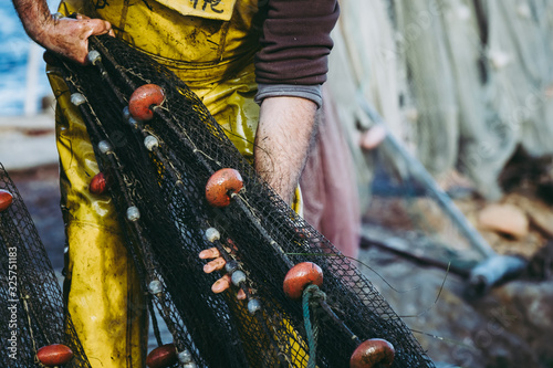 Mains d'un pêcheur en train de ranger ses filets de pêche photo