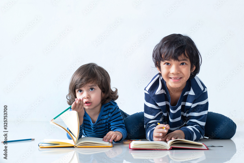 Smiling little boy drawing lying on the floor, over white background Smiling little boy drawing lying on the floor, over white background