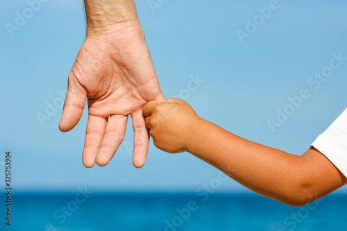 happy dad holds the hand of a child by the greek sea in nature © Kostia