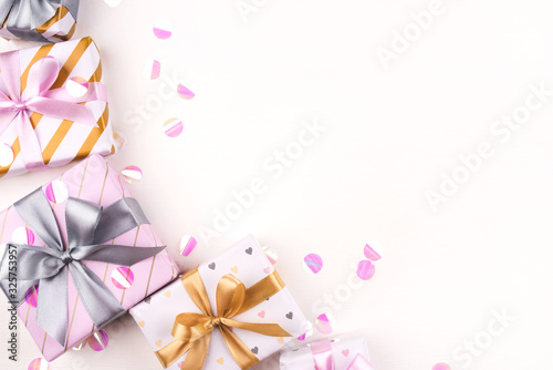 Several gift boxes with bows and confetti on a white background. Flat lay composition. Birthday  christmas  wedding or another holiday concept.