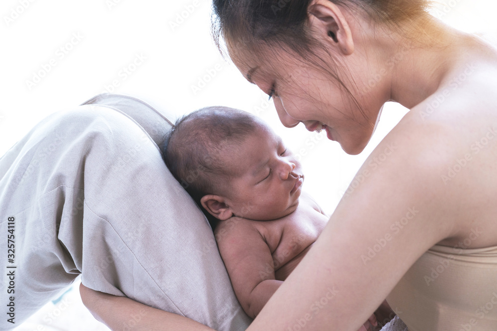 Asian newborn baby sleeps on mother's knee, mother looking and smile, newborn concept Asian newborn baby sleeps on mother's knee, mother looking and smile, newborn concept