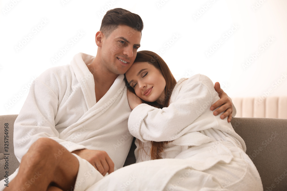 Happy couple in bathrobes on sofa at home Happy couple in bathrobes on sofa at home