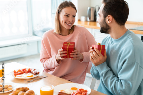 Portrait of happy couple holding gift boxes while having breakfast