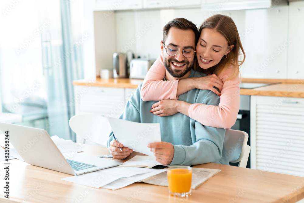 Portrait of smiling couple hugging while working with documents Portrait of smiling couple hugging while working with documents