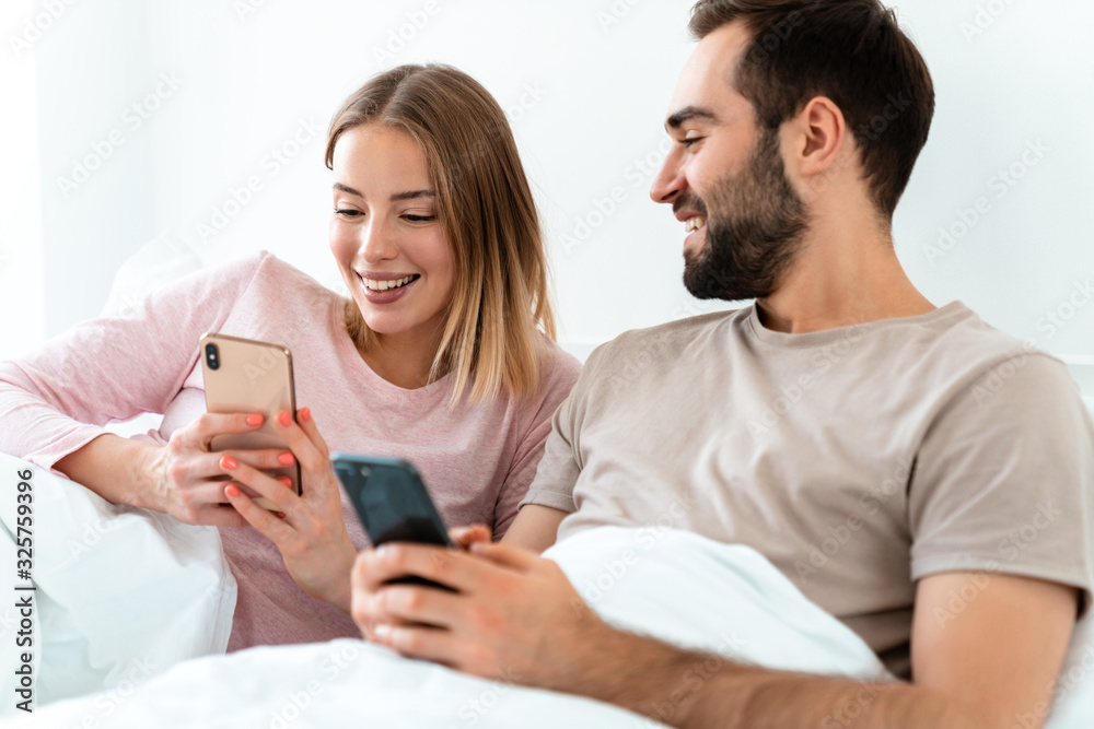 Portrait of beautiful joyful couple smiling and using smartphones Portrait of beautiful joyful couple smiling and using smartphones