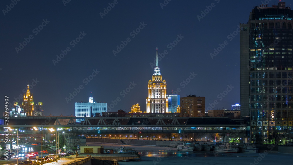 Hotel Ukraine and pedastrian bridge timelapse, landmark near historic center of Moscow. Cityscape in snowy winter evening. - obrazy, fototapety, plakaty 
