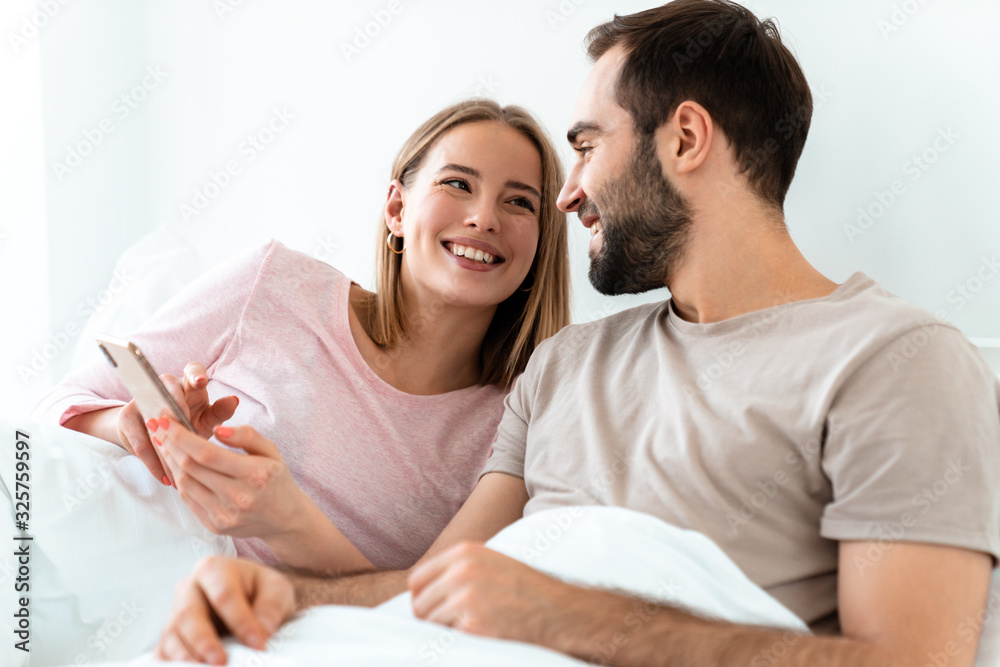 Portrait of beautiful joyful couple smiling and using smartphone Portrait of beautiful joyful couple smiling and using smartphone