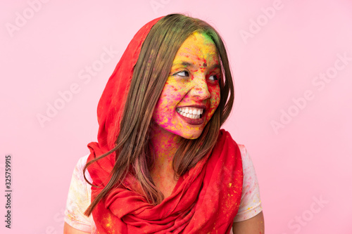 Young Indian woman with colorful holi powders on her face isolated on pink background