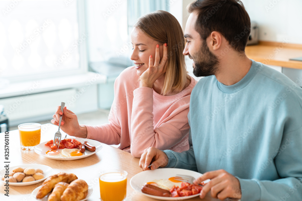 Portrait of young happy couple eating together while having breakfast Portrait of young happy couple eating together while having breakfast
