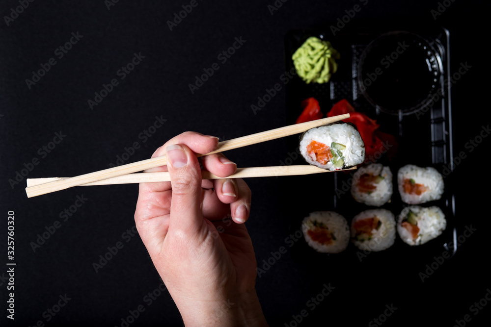 Eating with sticks sushi on black background. Eating with sticks sushi on black background.