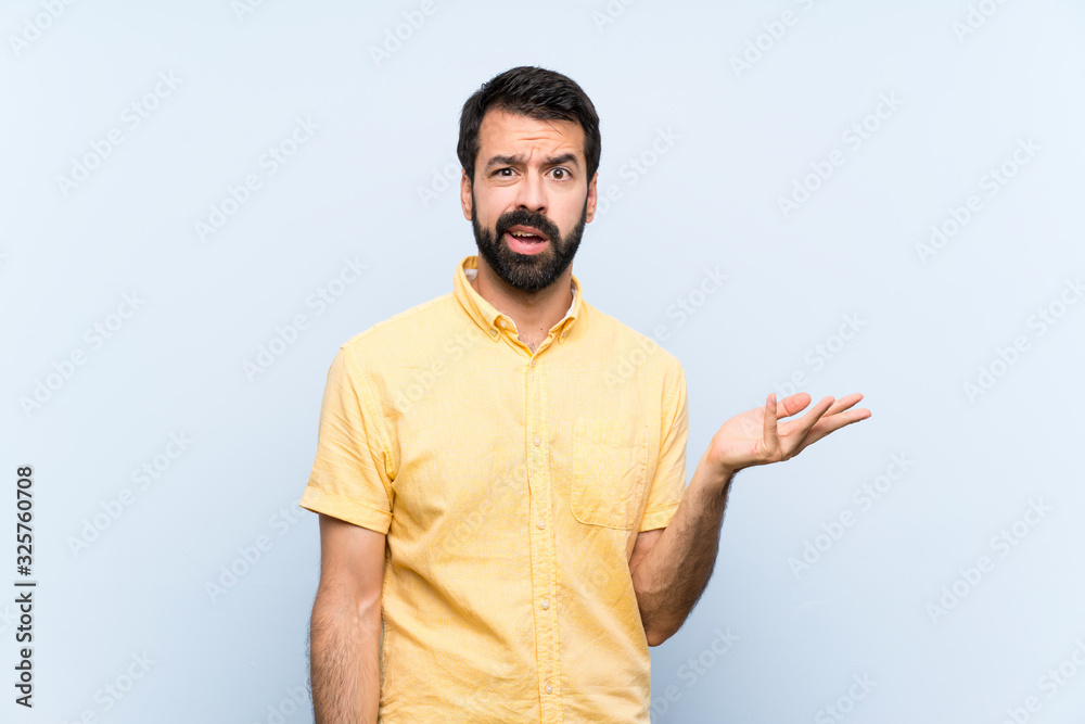 Fototapeta premium Young man with beard over isolated blue background making doubts gesture
