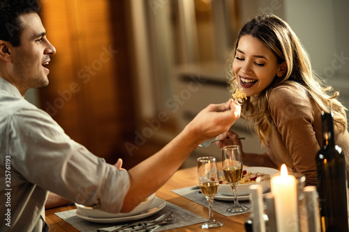 Happy man feeding her girlfriend during dinner at dining table. photo