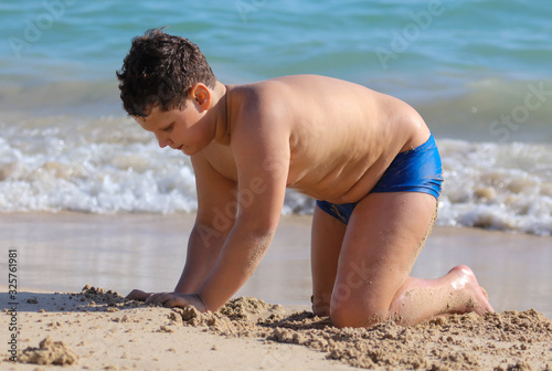 A boy plays in the sand on the seashore