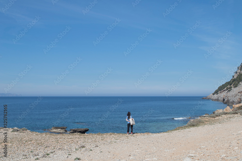 Chica con bolsa mirando hacia el horizonte del mar mediterraneo
