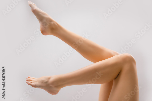 cropped perfect smooth and soft woman's legs on white background. side view © Roman