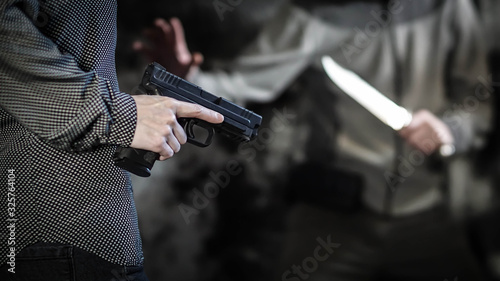 Woman using handgun to defend against knife-weilding attacker. Women's personal defense and concealed carry concept