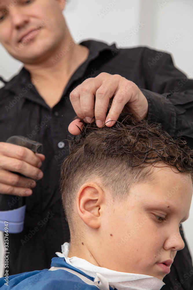 Obraz premium The hairdresser is watering the hair of a boy in the salon