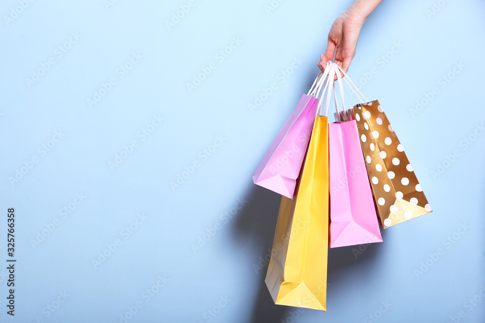 bags for shopping in hand on a colored background. Paper bags for shopping. A place to insert text, minimalism.